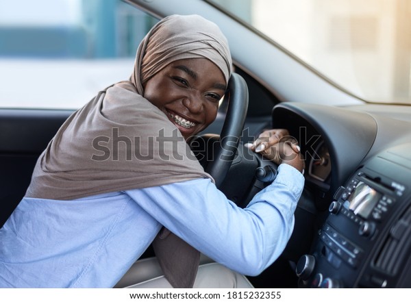 First\
Car. Happy Black Muslim Woman In Hijab Hugging Steering Wheel,\
Bought New Vehicle, Sitting In Auto In Dealership Center Showroom,\
Smiling At Camera, Closeup Shot With Copy\
Space