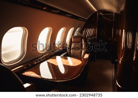 A first class area in a business jet with the sunset through a window