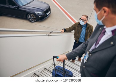 First Class Passenger In A Face Mask Ascending The Stairs Accompanied By The Airline Employee