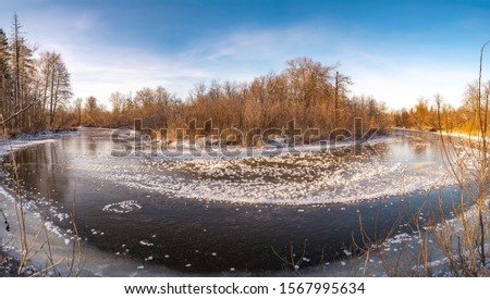 The first clear river ice is dotted with fluffy crystals of frost. Bend in the river Izh, Yakshur-Bodyinsky district of the Udmurt Republic, Russia.