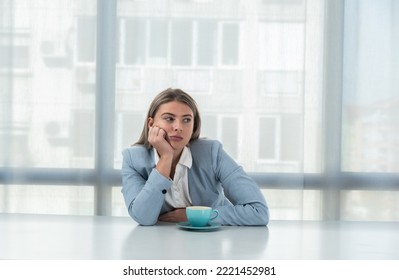 But First Coffee. Young Tired Business Woman In Formal Wear Sitting In The Office At Empty Desk With Cup Of Coffee. Female White Collar Worker, Freelancer Financial Expert Morning Routine.