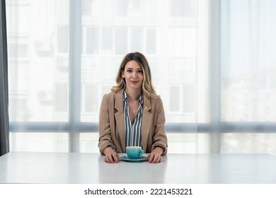 But First Coffee. Young Tired Business Woman In Formal Wear Sitting In The Office At Empty Desk With Cup Of Coffee. Female White Collar Worker, Freelancer Financial Expert Morning Routine.