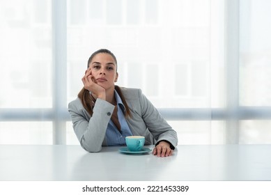 But First Coffee. Young Tired Business Woman In Formal Wear Sitting In The Office At Empty Desk With Cup Of Coffee. Female White Collar Worker, Freelancer Financial Expert Morning Routine.