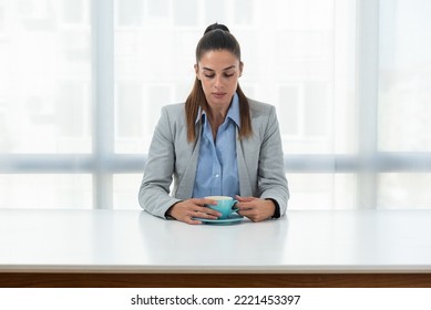 But First Coffee. Young Tired Business Woman In Formal Wear Sitting In The Office At Empty Desk With Cup Of Coffee. Female White Collar Worker, Freelancer Financial Expert Morning Routine.