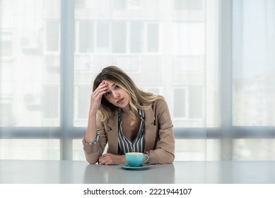 But First Coffee. Young Unhappy Tired Business Woman In Formal Wear Sitting In The Office At Empty Desk With Cup Of Coffee. Female White Collar Worker, Freelancer Financial Expert Morning Routine.