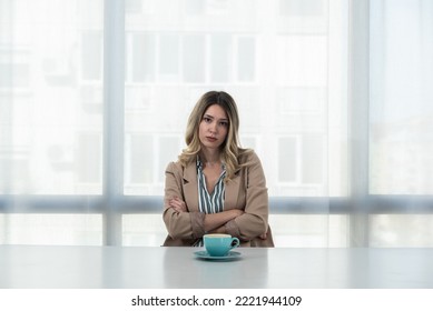 But First Coffee. Young Unhappy Tired Business Woman In Formal Wear Sitting In The Office At Empty Desk With Cup Of Coffee. Female White Collar Worker, Freelancer Financial Expert Morning Routine.