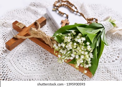 First communion or baptism composition with prayer book, rosary, cross and flowers lying on the table