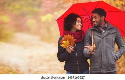 First date. Young couple walking under umbrella at rainy autumn day, free space