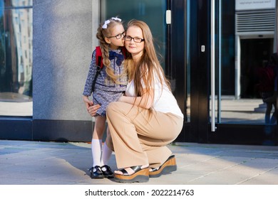 first day in the fall. back to school kids. mother lead little schoolgirl in uniform, schoolbag in the first grade. start of lessons. child kiss mom for goodbye.