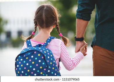 first day at school. father leads a little child school girl in first grade - Shutterstock ID 1151079065