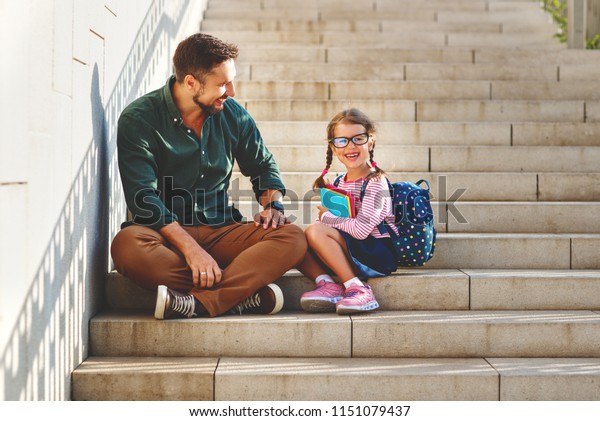 first day at school. father leads a little child\
school girl in first\
grade\
