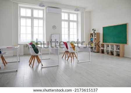 First day of school. Interior of modern light class elementary, middle school or high school without teacher and students. Bright school room with white desks, chairs and blackboard.