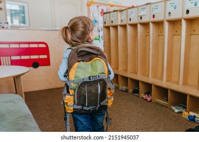 First day at school or kindergarten. Back view of little girl with backpack going inside the school. Back to school concept.
