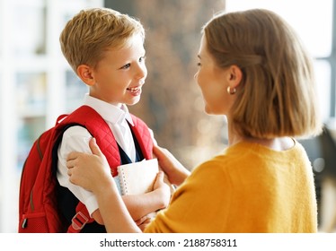 First day at school. Mother adjusts the briefcase to her happy son  during the  preparing   for school studies  at home