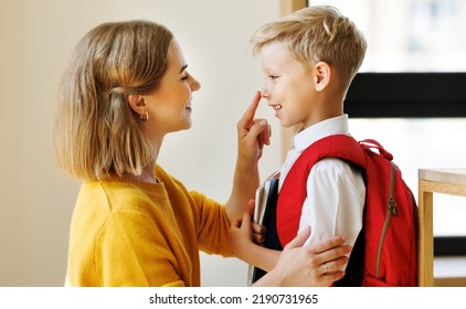 First day at school. Mother adjusts the briefcase to her happy son  during the  preparing   for school studies  at home - Shutterstock ID 2190731965