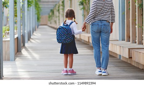 First Day At School. Mother Leads A Little Child School Girl In First Grade
