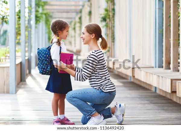 first day at school. mother leads a little child\
school girl in first\
grade\
