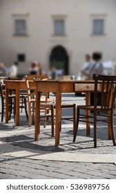 First Floor With Table And Chairs In A Historic Square In Central Italy, Perspective View, Blurred Background