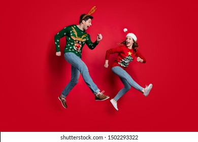 I'm First! Full Body Photo Of Excited Jumping Couple Rushing For X-mas Discounts Wear Ugly Ornament Jumpers Isolated Red Color Background