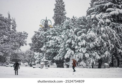 the first heavy snowfall in the city with people covering themselves with umbrellas - Powered by Shutterstock