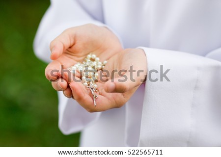 First Holy Communion concept - close up on rosary on child's hands