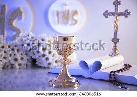 First holy communion concept. Golden chalice, altar cross, bible, grapes, bread and white flowers. Christianity theme background. 