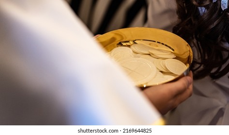 First Holy Communion, a host in a golden vessel in the boy's hands. Child in communion outfit holding a golden dish with communicants. The celebration of the first Holy Communion in the Roman Catholic