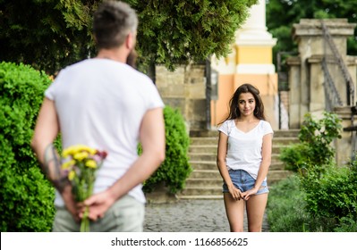First impression always important. Man hides flower bouquet behind back waits romantic date. Surprise for her. Dating tips that will transform your love life. Couple meeting for date park background.