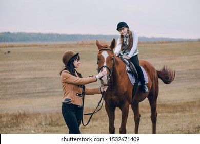 First lessons of horseback riding. Mom and daughter learn to ride a horse.   - Powered by Shutterstock