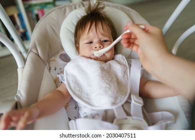 First Meal Feeding Small Caucasian Baby With Spoon Hands Of Unknown Mother Giving Food To Her Daughter Child With No Appetite Refusing To Eat Growing Up Problems