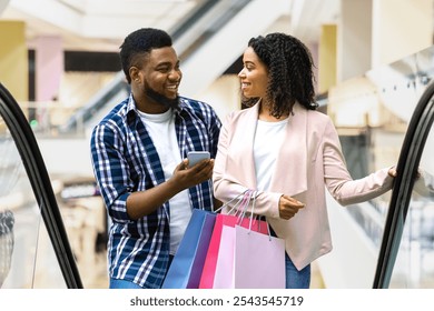 First Meet. Handsome Black Man Introducing With Beautiful Woman In Shopping Center, Asking Her Phone Number While Riding Escalator Together In Department Store, Woman Smiling In Return, Free Space - Powered by Shutterstock