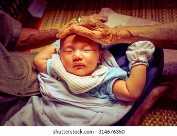 The First Meeting Of Asian Baby Infant With Great-grandparents. Great Grand Father Carrying Baby Placed On The Lap And Great Grand Mother Gently Pat On The Head.