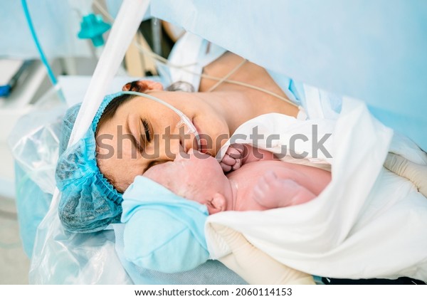 The first\
moments of mother and newborn after childbirth. Newborn child\
seconds and minutes after birth. Premature baby boy delivered by\
Caesarean section, being shown to his\
mother.