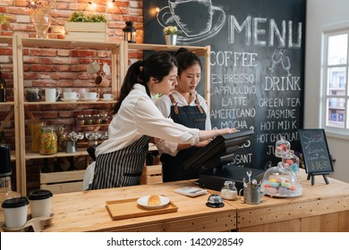 First Part Time Job In Summer Concept. Professional Barista Teaching Young Girl New Employee How To Using Tablet To Take Customer Order In Cafe Bar Counter In Coffee Shop. Coworkers Help Each Other