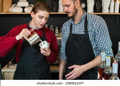first or part time or summer job concept. professional barista teaching young man how to prepare cappuccino or latte.