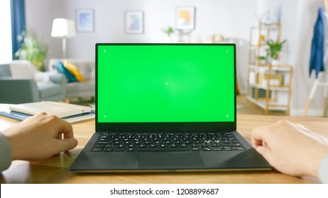 First Person Close-up Shot Man Uses Laptop With Green Mock-up Screen While Sitting At The Desk In His Cozy Living Room.