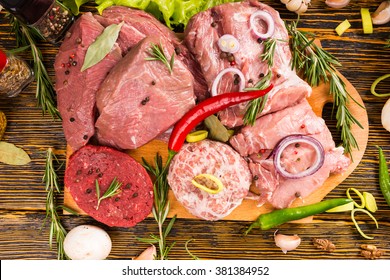 First Person Perspective Of And Abundance Of Raw Beef And Pork With Seasonings Surrounded By Wood Grain Table