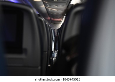 A First Person Perspective Of An Aisle Of Seats On A Commercial Airliner.