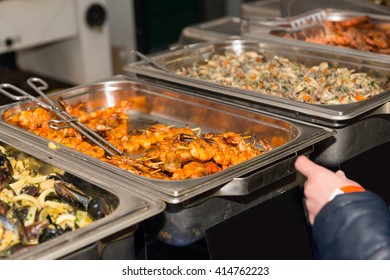 First Person Perspective Of Customer Perusing Offerings At Restaurant Buffet Or Food Festival, Pausing In Front Of Steamer Tray With Grilled Shrimp Skewers