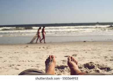 First Person Perspective Of A Man Lying On The Beach, Looking At A Couple