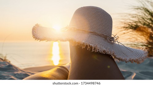 First Person Perspective Of Woman Legs With Straw Hat On Sunset Beach