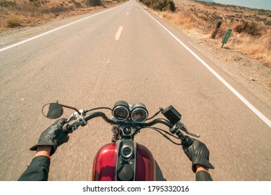 A first person point of view angle riding on the back from a motorcycle rider riding on an empty road on a sunny day with a red bike.