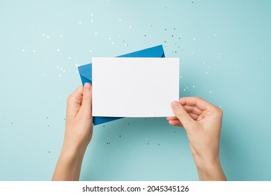 First person top view photo of hands holding blue envelope and white card over sequins on isolated pastel blue background with blank space - Shutterstock ID 2045345126