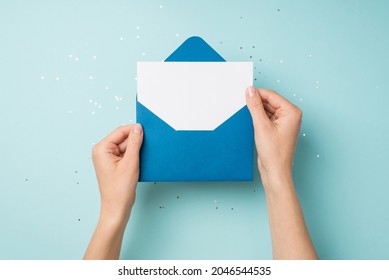 First person top view photo of hands holding open blue envelope with white card over sequins on isolated pastel blue background with empty space - Shutterstock ID 2046544535