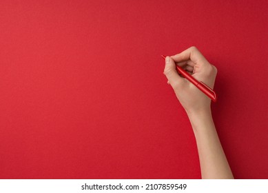 First person top view photo of valentine's day decorations female hand holding red pen on isolated red background with blank space