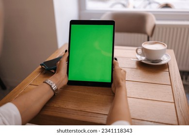 First person view of female hold digital tablet in cafe. Table with cup of coffee. Mock up of tablet. Green screen - Powered by Shutterstock