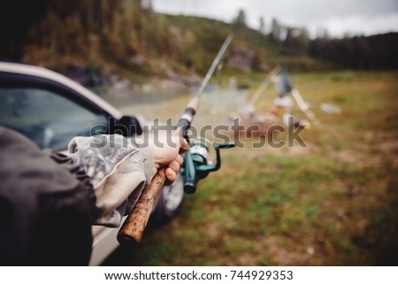 First person view, fisherman holding fishing rod for catching fish in his hand