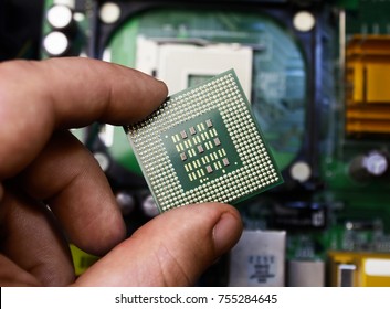 First Person View Hand Holding A Computer Processor Chip On Motherboard Background.