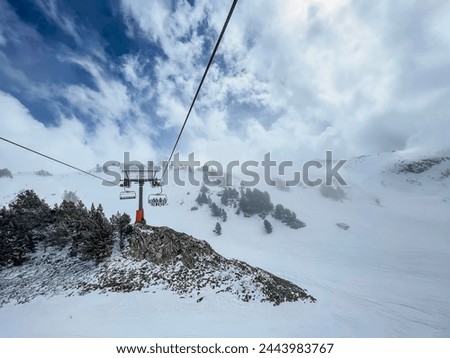 first person view of a ski resort chair on a day with some fog and clouds, winter ski resort, ski vacations in the snow, horizontal
