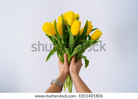 first person view. woman hold bouquet of yellow tulips. white background